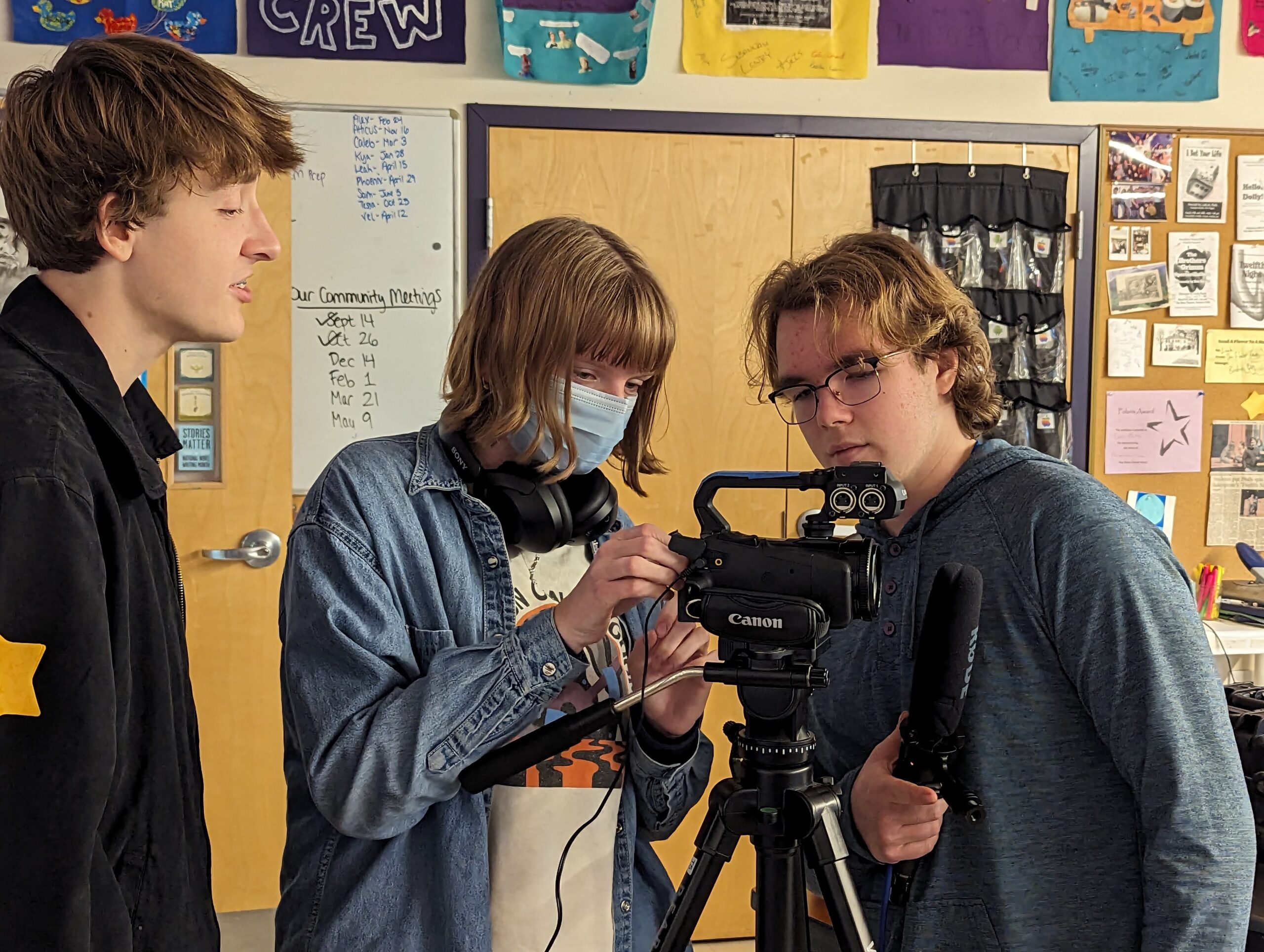 Three students gather around a video camera