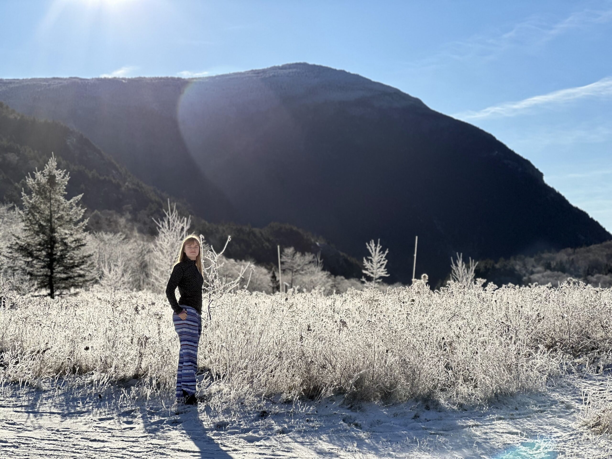 A student stands against a snowy backdrop in the mountains