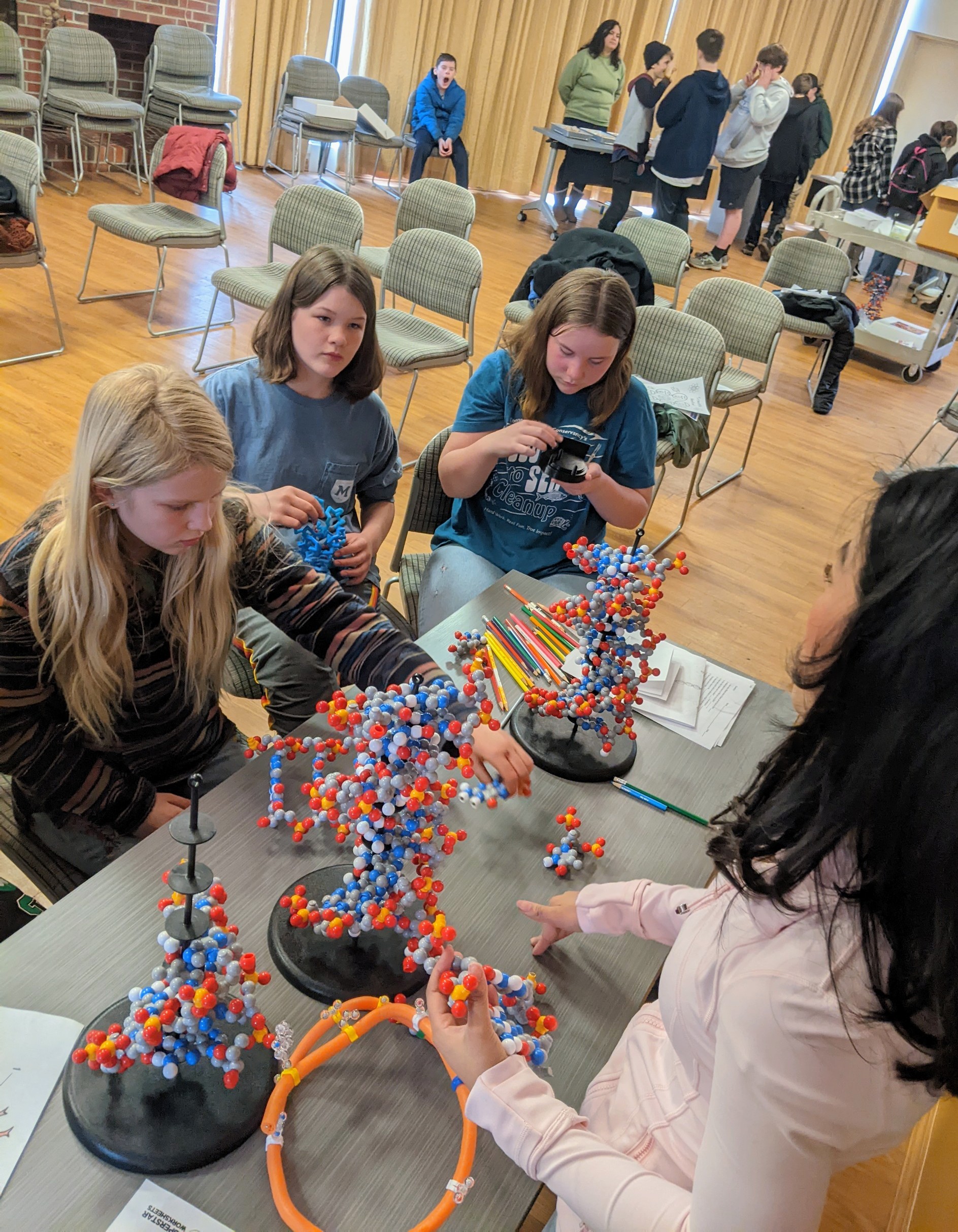 A group of students examine molecular structures with an instructor