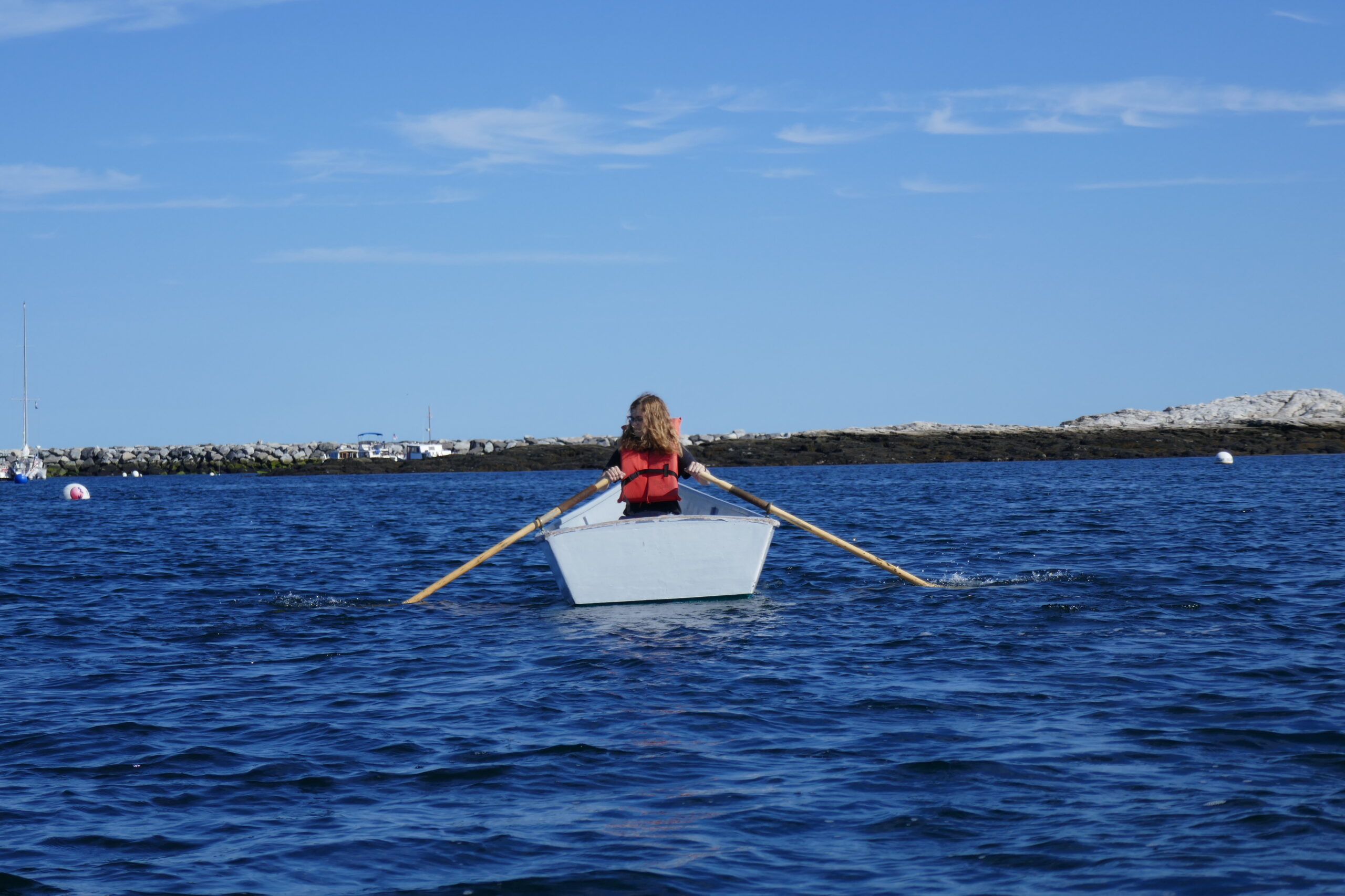 Student in a boat rows across a channel